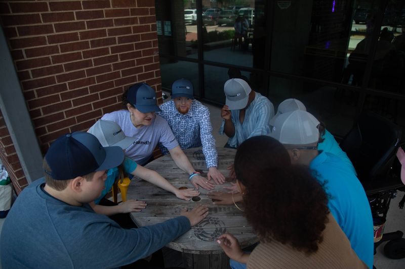 A group of young adults play a game together around a table.